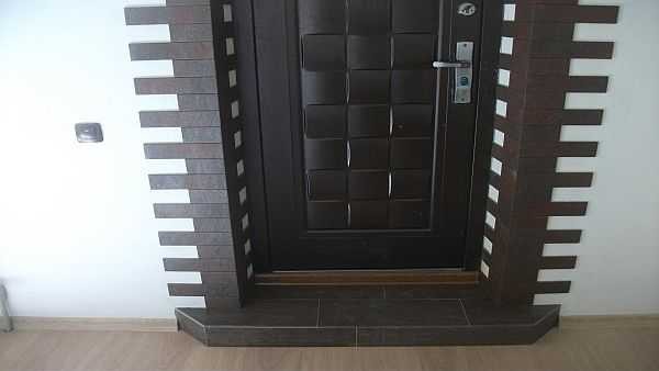 The outer slope of the entrance door can be finished with stone or tiles
