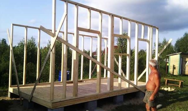 Puoliksi rakennettu lato: lattia ja kaksi pitkää seinää seisovat, jäljellä on lyhyiden asentaminen ja kattojärjestelmän tekeminen