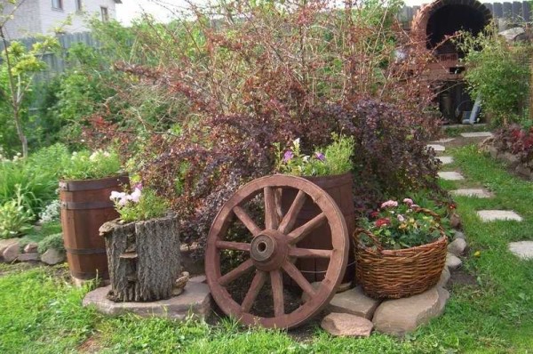 O design do jardim rústico é facilmente reconhecível pela presença de rodas de carrinhos, cestos, pratos de cerâmica, que são usados ​​das formas mais inesperadas