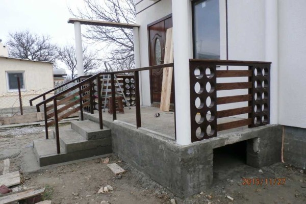 Vienas iš betoninės verandos su mediniais turėklais variantų