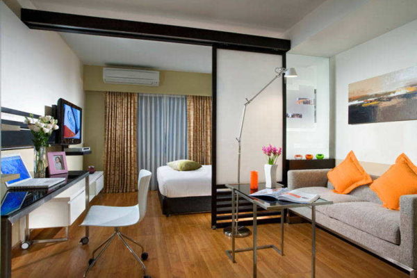 Uma cama em uma sala de estar com um quarto dedicado geralmente é colocada longe da entrada.