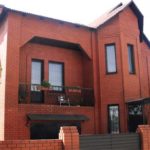Fațada unei case din cărămidă roșie cu două etaje, cu trăsături caracteristice unui stil modern, dar cu un caracter individual clar